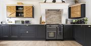 A modern country chic kitchen with large range cooker, open plan space, white walls and dark blue cupboards.