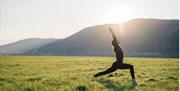 a person doing a yoga pose in the field