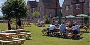 View of a large lawned pub garden with outdoor wooden seating