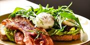 place of gourmet breakfast, poached eggs and bacon with rocket on toast