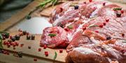 prepared raw venison steaks with junipers on a chopping board