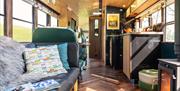 Interior view of the Skoolie Stays glamping bus showing lounge and kitchen area