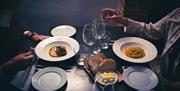 table with plates of food and people's hands