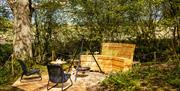 Outdoor seating and wood-fired hot tub deck beside the Eco-Cabin among trees