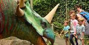 Adults and children enjoying looking at an enormous triceratops with a big horn and beak-like mouth