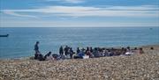 Group on the beach in the sunshine having a safety briefing before heading into the water
