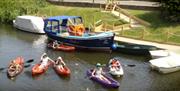 A photo of our jetty on the River Rother with kayaks, rowing boats and our ferry.