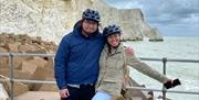 A couple smiling for the camera with white cliffs behind them