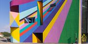 An external photo of the Towner Gallery in Eastbourne, the walls are an abstract pattern of very bright colours.