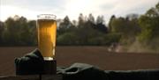 Pint of beer with the field behind the brewery in the background