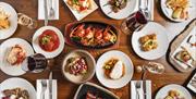 a birds eye view of a range of tapas plates on a wooden table showing the range of the menu