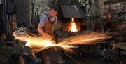 A blacksmith fire welding with arcs of fire sparks around him