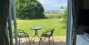 A view through the double doors with table and chairs in front of view of parkland and distant fields and hills.
