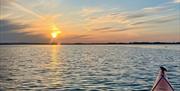 A sunset view over Chichester Harbour from an orange kayak