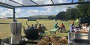 coffee pot and croissants at the outdoor kitchen with people sitting in the background